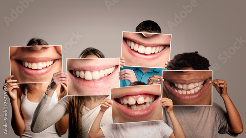 group of happy people holding a picture of a mouth smiling on a gray background
