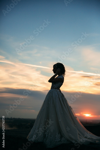 Silhouette of girl in wedding dress. Summer sunset