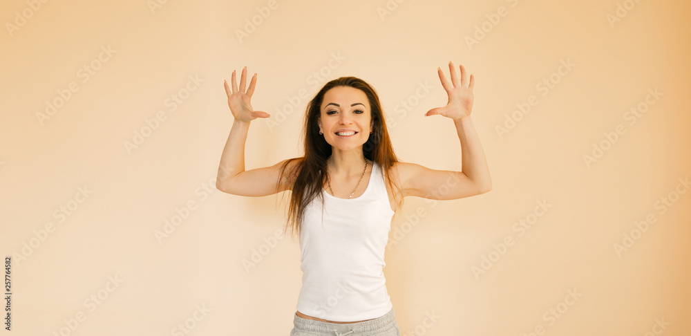 a young girl in a white T-shirt on a uniform beige background makes an emotion of happiness, rejoices, smiles, shows lashes a young girl in a white T-shirt on a uniform beige background makes an emotion of happiness, rejoices, smiles, shows lashes