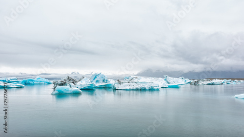 Jokulsarlon glacial lagoon lake in Iceland with many icebergs floating on water by Vatnajokull mountains snow clouds © Kristina Blokhin