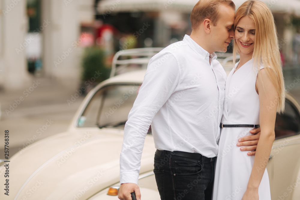 Man and woman stand near old car with umbrella. Beautiful couple in the city. Black umbrella. Black and white clothes Man and woman stand near old car with umbrella. Beautiful couple in the city. Black umbrella. Black and white clothes