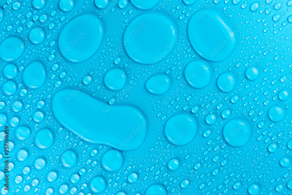 Droplets of water on a blue, matte background illuminated with a delicate light.