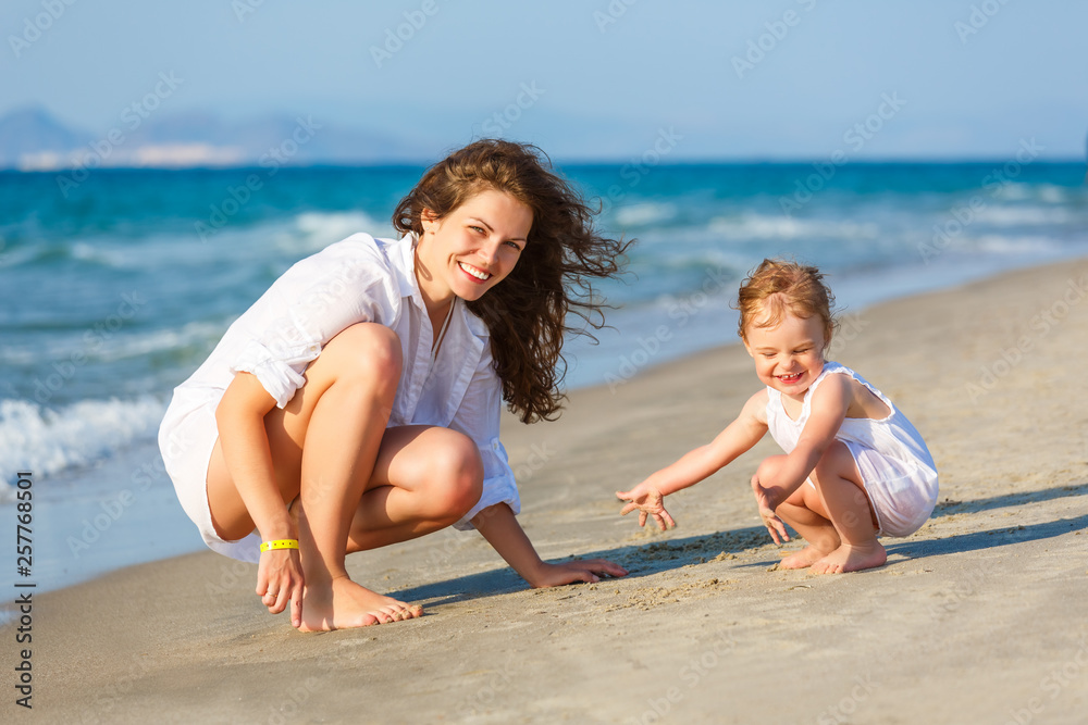 Mother and little daughter playing on the sea beach in Greece Mother and little daughter playing on the sea beach in Greece