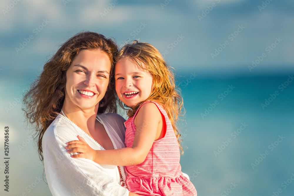 Portrait of happy mother and little daughter on sunny beach on Maldives at summer vacation Portrait of happy mother and little daughter on sunny beach on Maldives at summer vacation