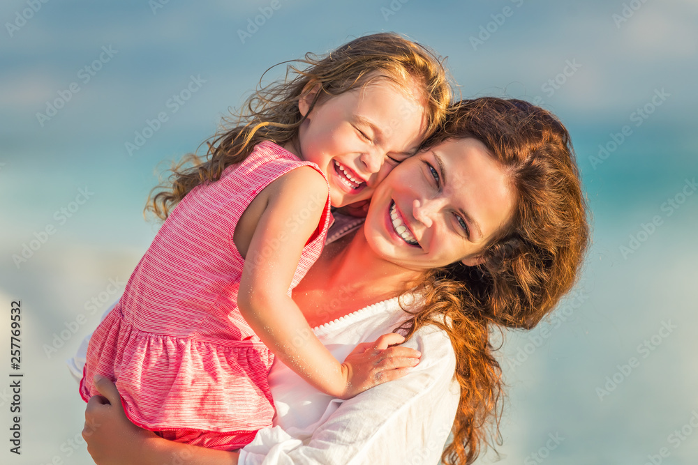 Portrait of happy mother and little daughter on sunny beach on Maldives at summer vacation Portrait of happy mother and little daughter on sunny beach on Maldives at summer vacation