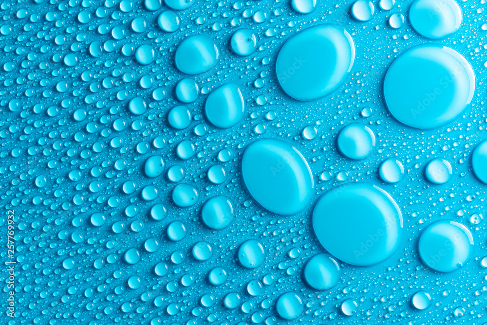 Droplets of water on a blue, matte background illuminated with a delicate light. Droplets of water on a blue, matte background illuminated with a delicate light.