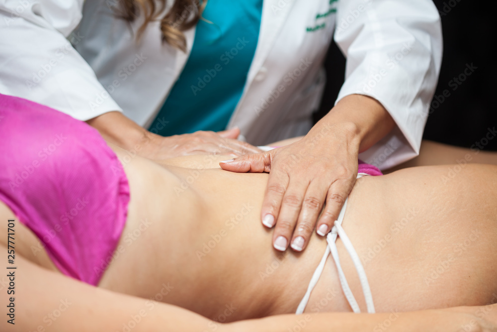 Doctor performing an abdominal massage on a young female patient