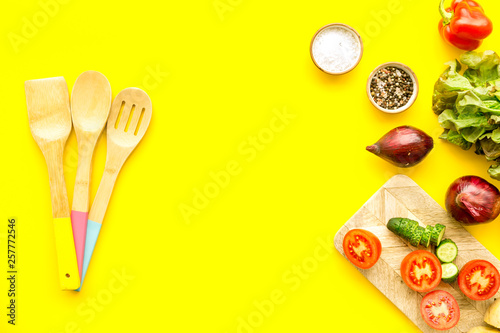 cooking with raw vegetables on yellow background top view