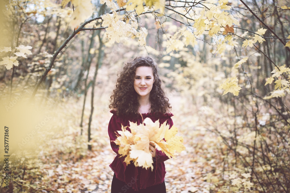 Happy girl in an atumn park holding maple leaves Happy girl in an atumn park holding maple leaves