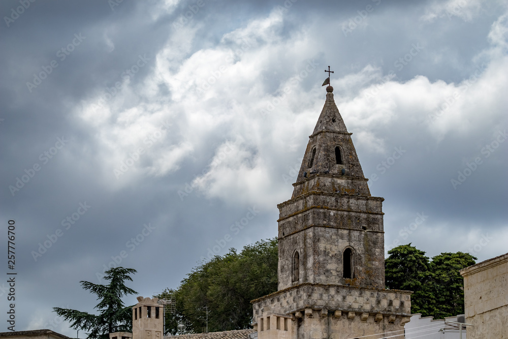 Fototapeta premium Summer blue sky and church roof with religious cross, view of ancient town of Matera, the Sassi di Matera, Basilicata, Southern Italy, cloudy summer August day