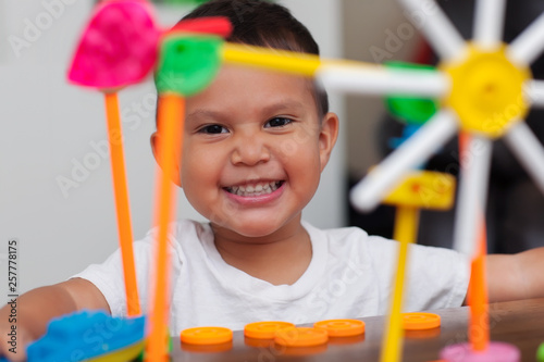 A hispanic boy with big smile while he plays with colorful building toys and learns to count with elementary manipulative toys.