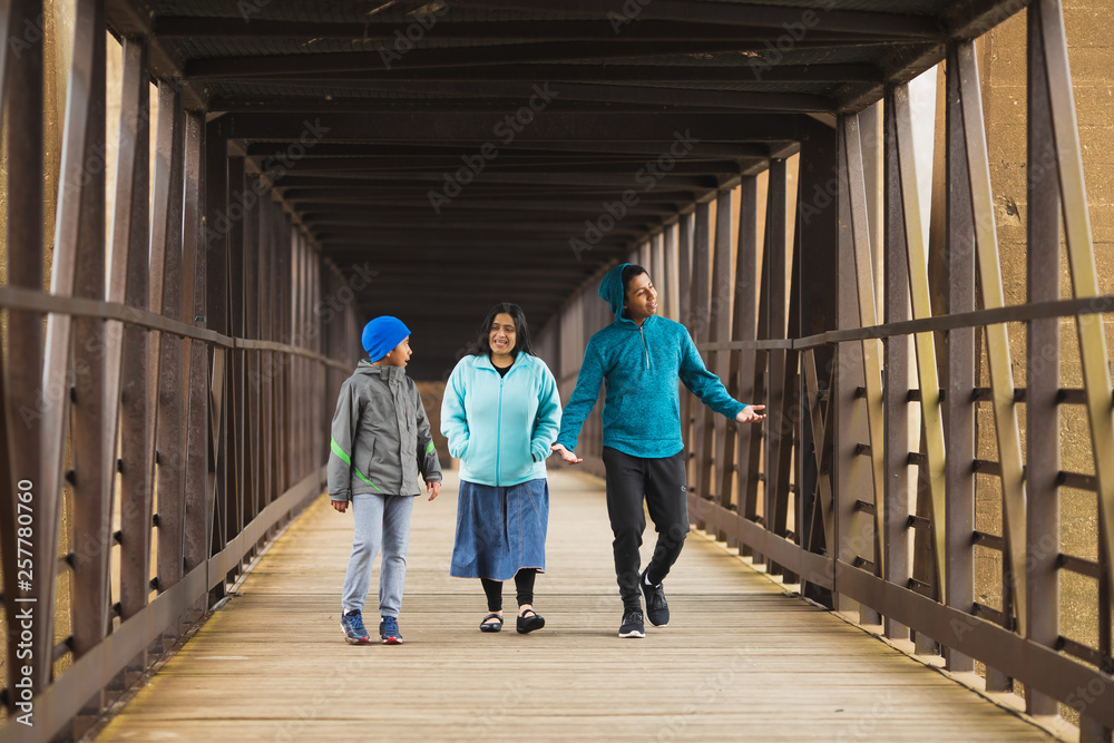 Fototapeta premium Hispanic Mother Walks With Sons On A Bridge