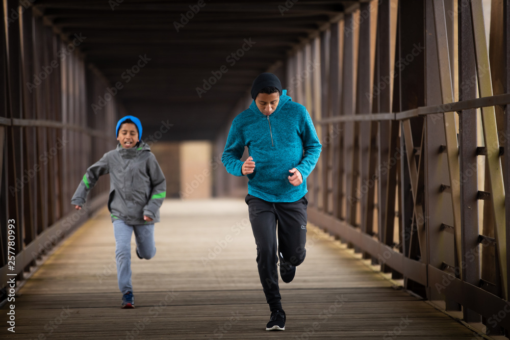 Obraz premium Two Hispanic Brothers Run A Race Down Bridge