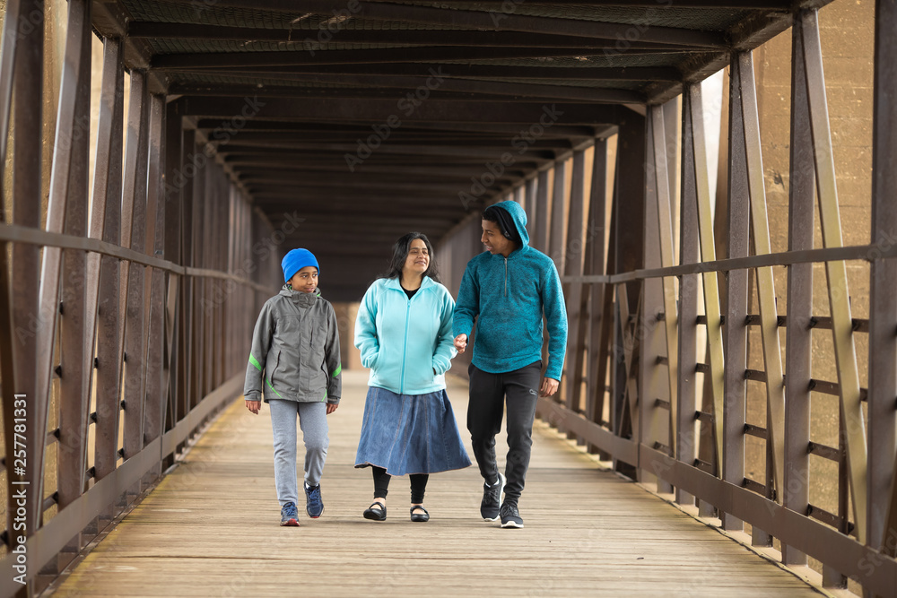Fototapeta premium Hispanic Mother Walks With Sons On A Bridge