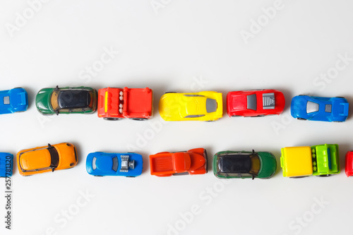 Plastic multi-colored toy cars are lined up on a white background. Stereotypical alignment of subjects is a sign of autism. Selective focus. Copy space for text. Traffic jams air pollution concept.