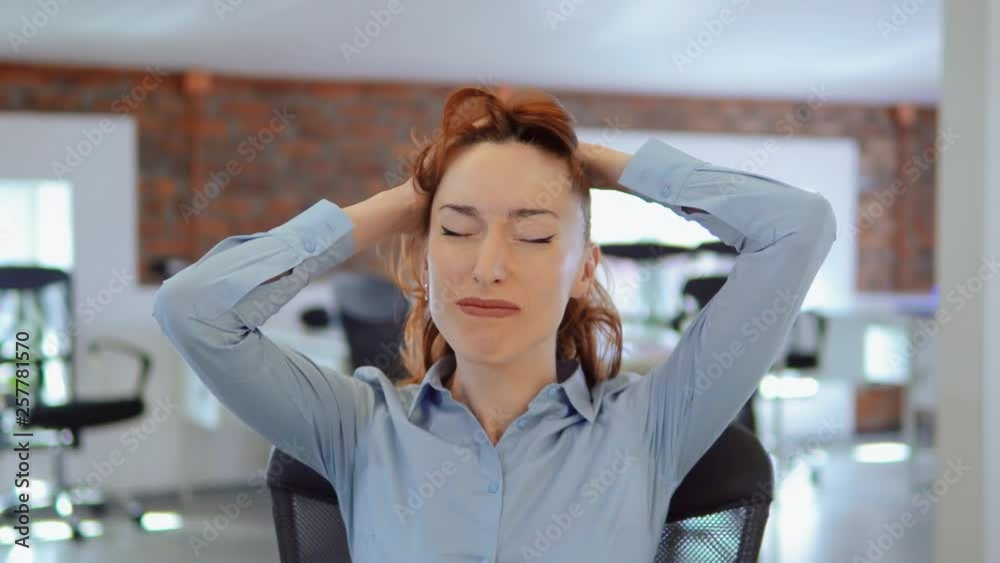 employee with red long hair showing negative emotions sick headache frustration looking at the camera front view. portrait young caucasian woman sitting at the workplace in modern office. employee with red long hair showing negative emotions sick headache frustration looking at the camera front view. portrait young caucasian woman sitting at the workplace in modern office.