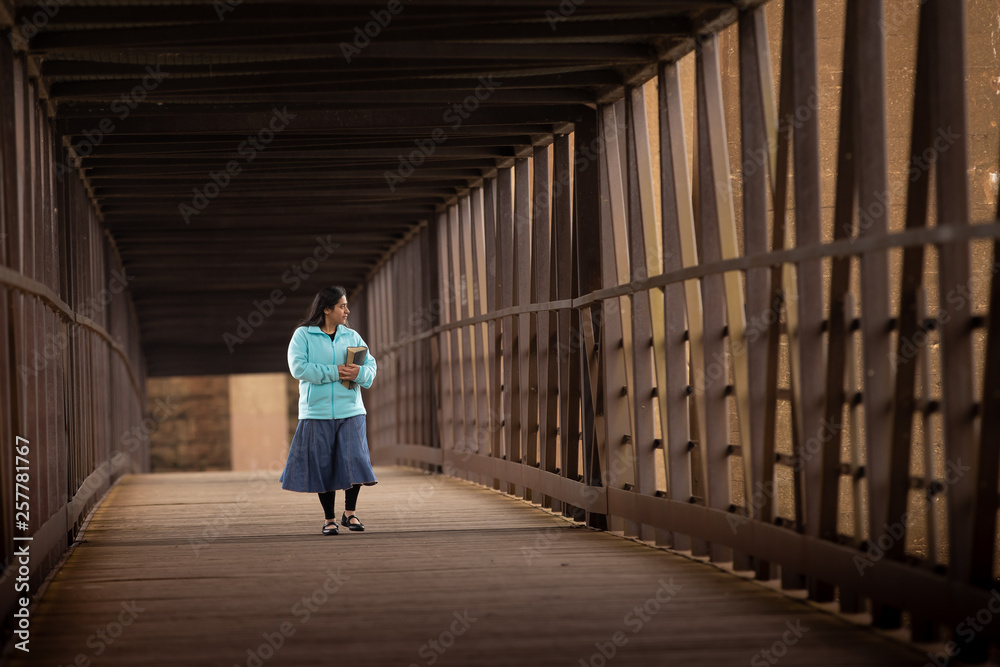 Hispanic Woman Walking Down A Bridge With her Bible