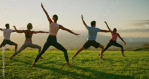 Yoga class at sunset, happy diverse group of young people practicing yoga poses together, stretching health and wellness photo