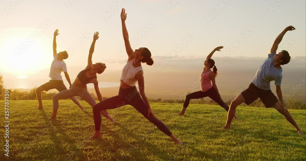 Yoga class at sunset, happy diverse group of young people practicing yoga poses together, stretching health and wellness