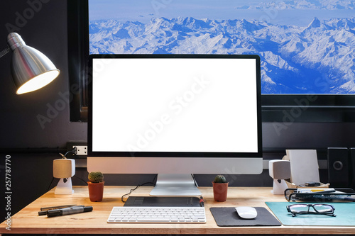 Graphic designer's workspace with a pen tablet, a computer and white backgroud for text with beautiful view of Snow moutain,France from Window