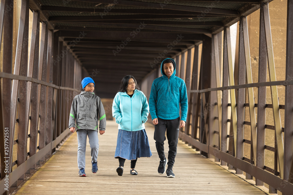 Hispanic Mother Walks With Sons On A Bridge