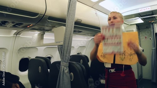 Gorgeous blonde stewardess in airplane explains rules about safety with use of the belt, mask during taking off and landing in case of any accident or crash. Profession concept. Close up
