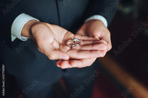 Close up of two wedding rings on groom's palms. 