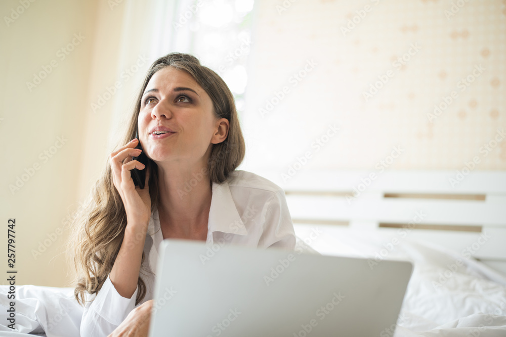 Happy Beautiful woman working on a laptop on the bed in the house Happy Beautiful woman working on a laptop on the bed in the house
