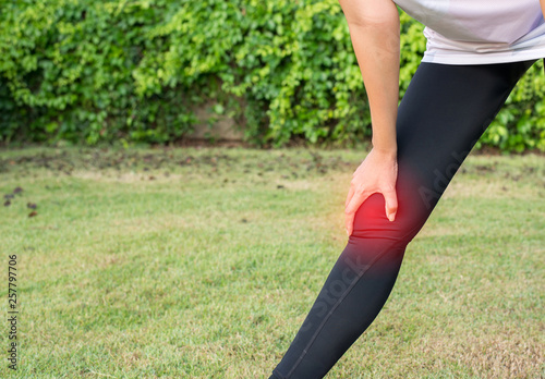 Hand touching her muscle knee after jogging at park,Woman runner suffering from pain in legs be injured