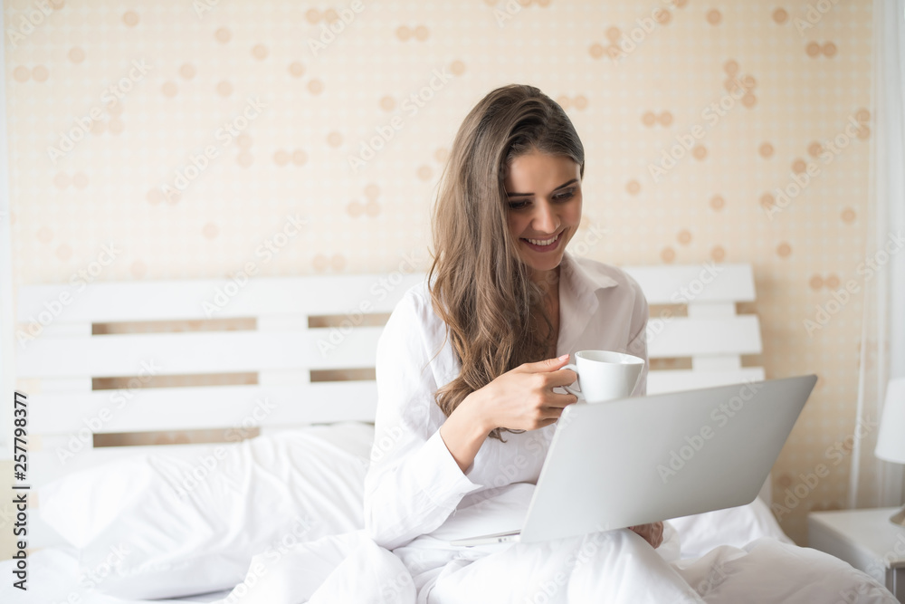 Happy Beautiful woman working on a laptop on the bed in the house Happy Beautiful woman working on a laptop on the bed in the house
