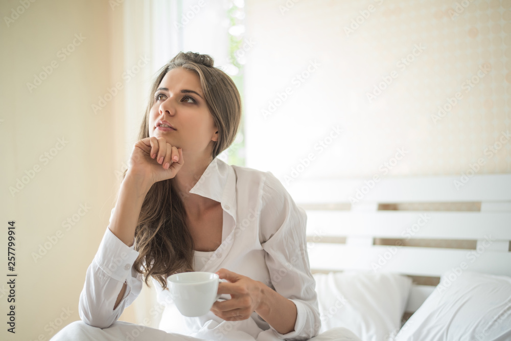 Beautiful woman at her bedroom drinking coffee in the morning Beautiful woman at her bedroom drinking coffee in the morning