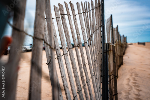 Wooden fence at beach with cars and sand in background