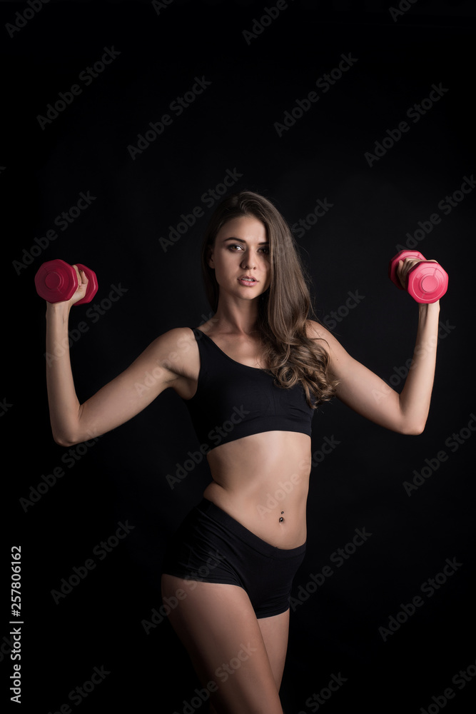 Portrait of young beautiful woman making physical exercises with dumbbells