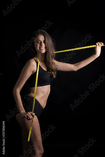 Portrait of beautiful young woman measuring her figure size with tape measure © Johnstocker