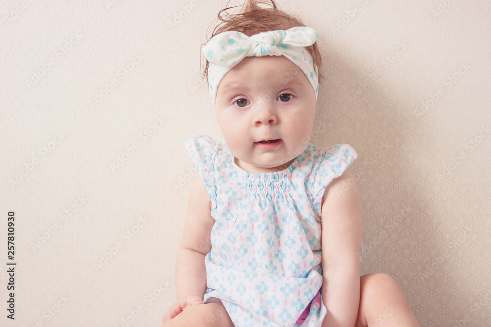 Portrait of eight month girl in the dress with headband, indoors, blurred background Portrait of eight month girl in the dress with headband, indoors, blurred background