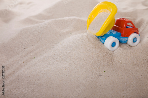 Small dump truck empties sand. Miniature. Children play in the sand. Sand therapy. Psychology and construction.