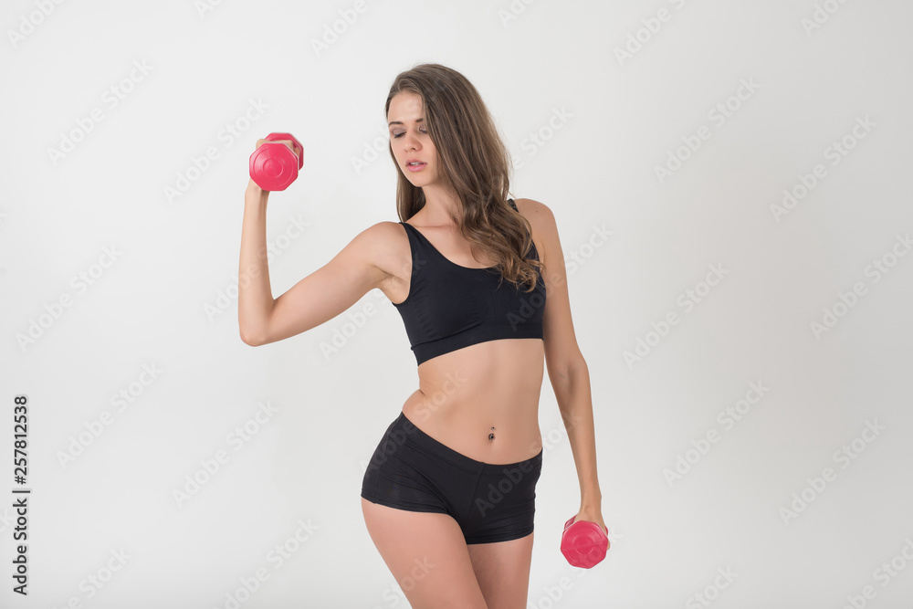 Portrait of young beautiful woman making physical exercises with dumbbells Portrait of young beautiful woman making physical exercises with dumbbells