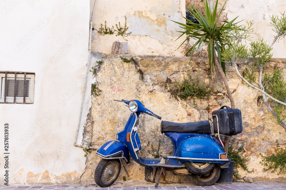 blue old scooter parked by the wall in the empty street Chania Crete