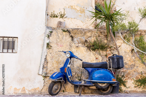 Fototapeta Naklejka Na Ścianę i Meble -  blue old scooter parked by the wall in the empty street Chania Crete