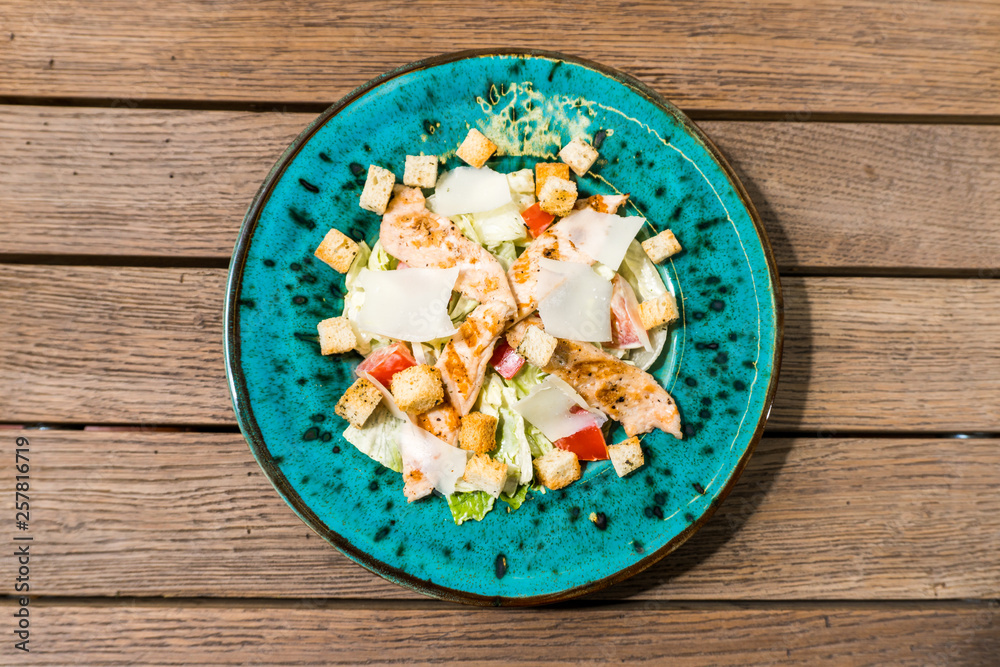 Fresh caesar salad in white plate on wooden table Fresh caesar salad in white plate on wooden table