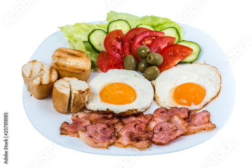 breakfast fried egg fresh vegetables fried bacon and olives on a white plate isolated