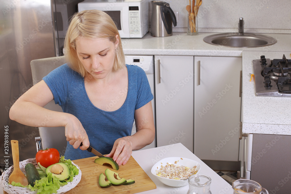 girl eating an avocado and salad, healthy eating, diet. pensive woman looks at the tomato. in the kitchen. bright room girl eating an avocado and salad, healthy eating, diet. pensive woman looks at the tomato. in the kitchen. bright room