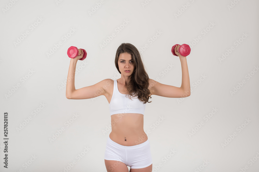 Portrait of young beautiful woman making physical exercises with dumbbells Portrait of young beautiful woman making physical exercises with dumbbells