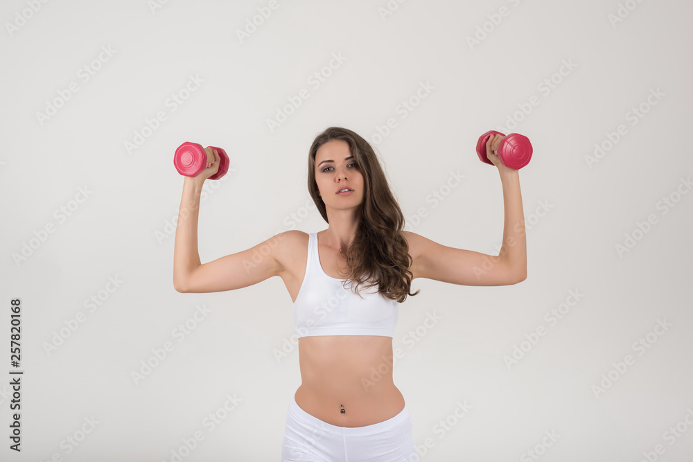 Portrait of young beautiful woman making physical exercises with dumbbells Portrait of young beautiful woman making physical exercises with dumbbells