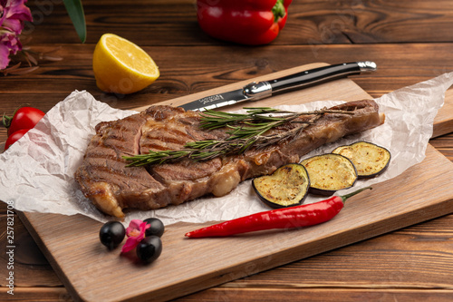 Grilled steak with lemon on a board on a wooden background