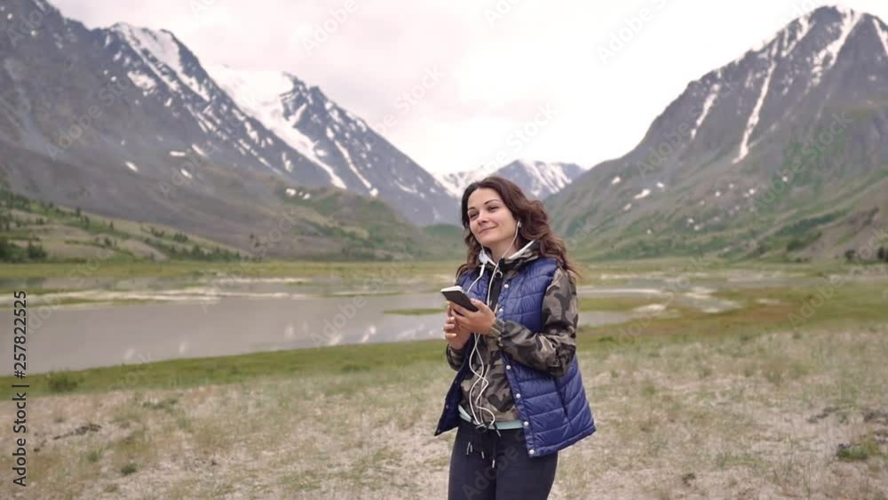 woman tourist in headphones dancing on a background of mountains and scenery. tourist trip woman tourist in headphones dancing on a background of mountains and scenery. tourist trip