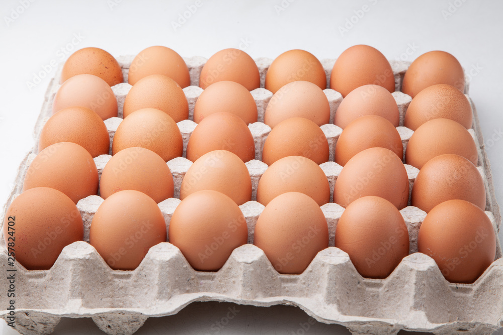 A tray of yellow homemade chicken eggs on a white background. A tray of yellow homemade chicken eggs on a white background.