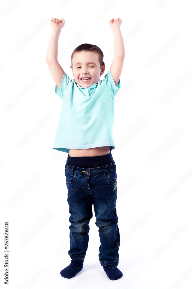 Little smiling boy with dark hair in blue jeans, blue polo t-shirt is jumping and having fun on an isolated white background in a photo studio Little smiling boy with dark hair in blue jeans, blue polo t-shirt is jumping and having fun on an isolated white background in a photo studio
