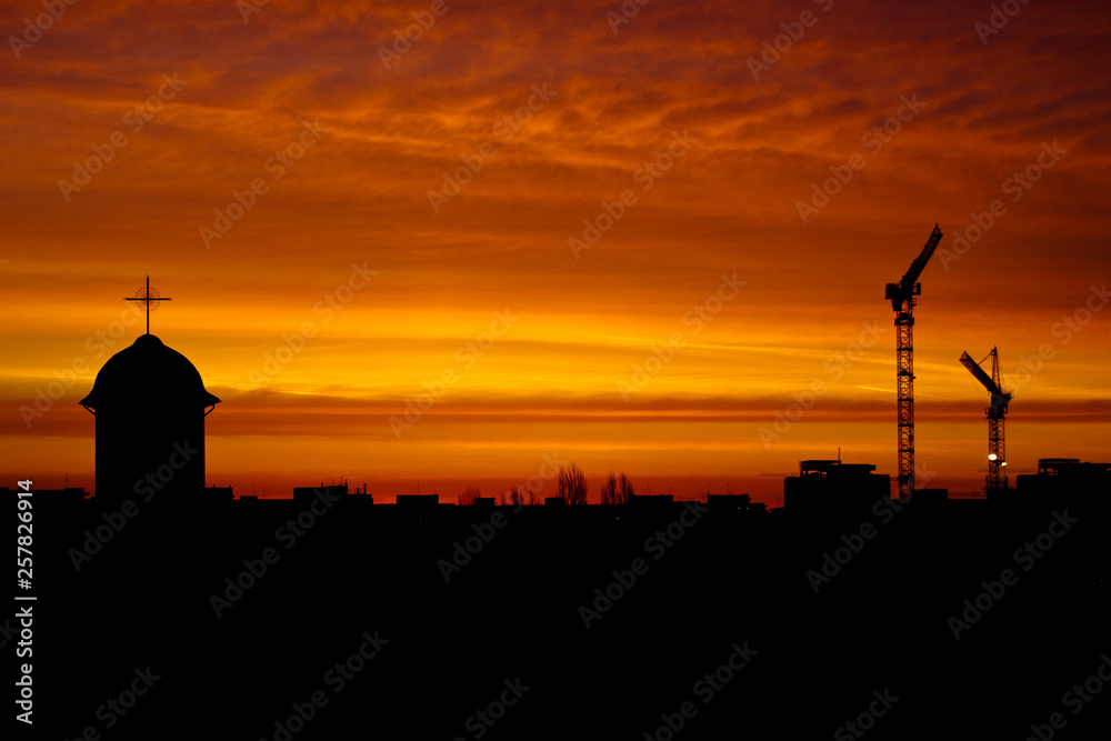 Church and cranes silhouettes at dusk