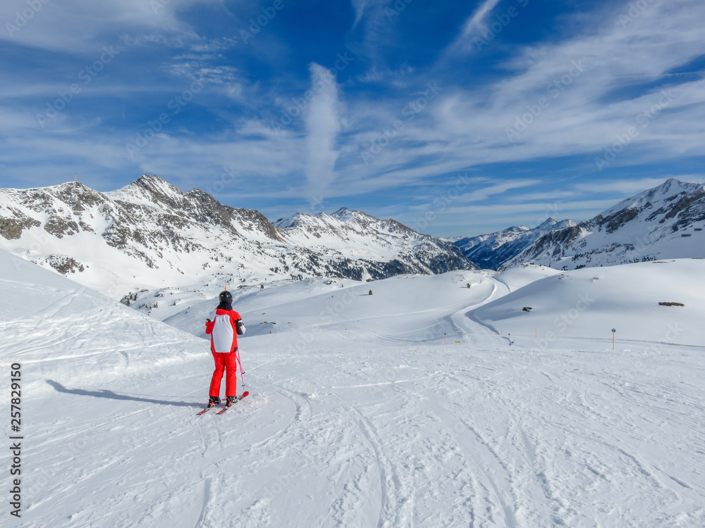 Single skier on empty ski slope in Austrian Alps. Amazing view downhill, perfectly prepared ski slopes, crisp snow. Amazing way to spend spring getaway, relaxing, sporting and enjoying the nature.